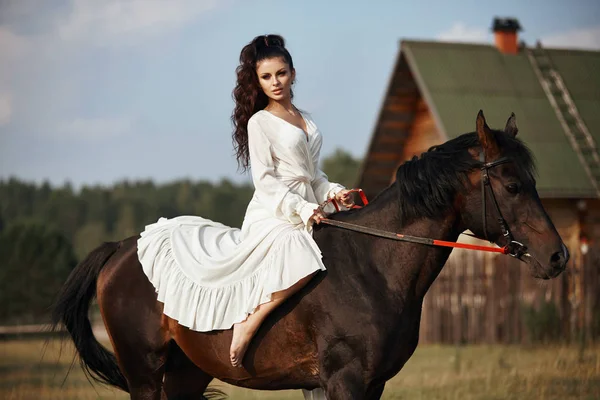 Mädchen in einem langen Kleid reitet ein Pferd, eine schöne Frau reitet ein — Stockfoto