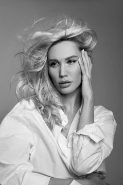 Saçları rüzgarda uçuşan sarışın bir kadın, beyaz gömlekli bir kızın yakın plan portresi, doğal makyaj ve temiz narin bir ten.