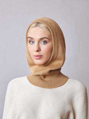 Kafasında başlık olan, sarı saçlı, Avrupalı Müslüman bir kadın. Yumuşak ciltli, doğal kozmetik ürünleri olan güzel bir kız.