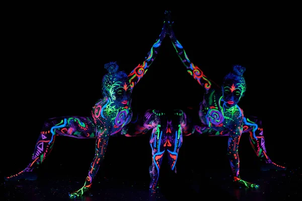 Art woman body art on the body dancing in ultraviolet light. Bright abstract drawings on the girl body neon color. Fashion and art woman