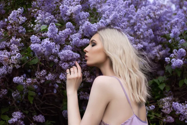 一个穿着紫色衣服的女人在紫丁香丛中的画像 一个穿着紫丁香花的女孩的脸靠得紧紧的 — 图库照片