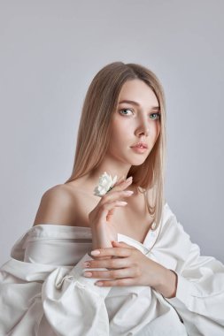 Sarışın güzel kadın elinde beyaz çiçek tutuyor. Güzel yumuşak eller ve yumuşak ten. Güzellik için kozmetik el bakımı