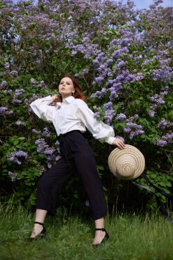 Baharda güzel bir kız çiçek açan leylak çalılarının dallarında Parlak bir yaz gününde bir kadının portresi