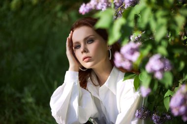 Baharda güzel bir kız çiçek açan leylak çalılarının dallarında Parlak bir yaz gününde bir kadının portresi