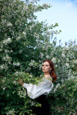 İlkbaharda çiçek açan elma çalılarının dallarında güzel bir kız. Parlak bir yaz gününde bir kadının portresi