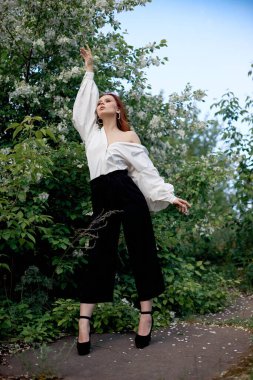 İlkbaharda çiçek açan elma çalılarının dallarında güzel bir kız. Parlak bir yaz gününde bir kadının portresi