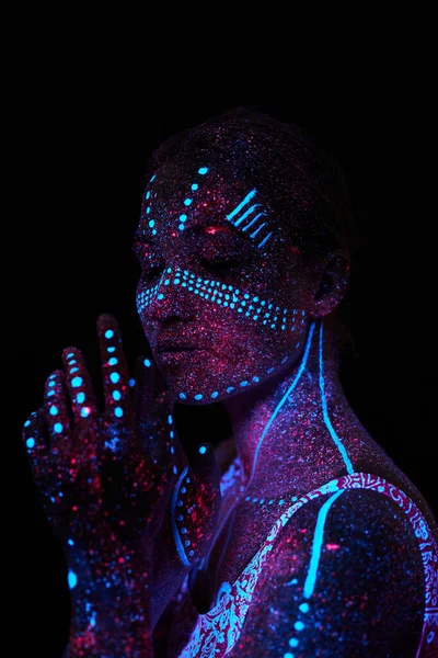 Art woman cosmos in ultraviolet light. Entire body is covered with colored droplets. Girl posing in the dark. Noise, out of focus