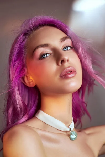 Portrait of a woman with bright colored flying hair, all shades of purple. Hair coloring, beautiful lips and makeup. Hair fluttering in the wind. Sexy woman with short  hair. Professional coloring