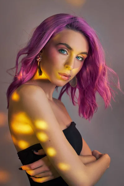 Portrait of a woman with bright colored flying hair, all shades of purple. Hair coloring, beautiful lips and makeup. Hair fluttering in the wind. Sexy woman with short  hair. Professional coloring