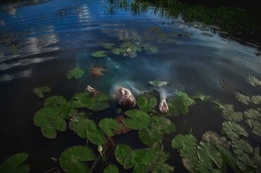 Genç bireyler yemyeşil nilüferlerle çevrili bir gölette huzur içinde yüzerler, sakin suyun tadını çıkarırlar ve açık bir günde mavi gökyüzünü yansıtırlar..