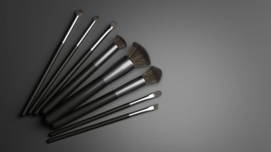 Çeşitli şekil ve boyutlara sahip çeşitli makyaj fırçaları pürüzsüz gri bir yüzey üzerinde düzgün bir şekilde düzenlenir, güzellik uygulaması için araçlar sergilenir.