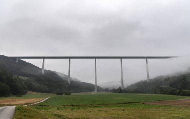 Kochertalbrucke, en yüksek Alman viyadük, bulutlar ve sabah sis piercing uzun sütunlar doğru giden bir sokak ile manzara.