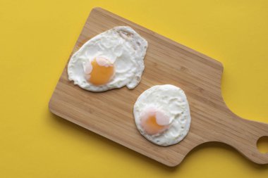 İki görünümünün üzerinde kızarmış yumurta sarı mutfak masasının üzerinde ağaç kesme tahtası