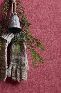 Bir tırnak, bir Noel çan ve köknar ağacı dal ile birlikte kırmızı duvar üzerinde handgloves çifti astı