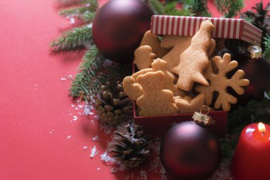 Noel görüntü tanımlama Xmas şekil, kırmızı Küre, yanan bir mum ve kar taneleri ile kırmızı bir arka plan üzerinde çam çırpı ile bir hediye kutusu ile.