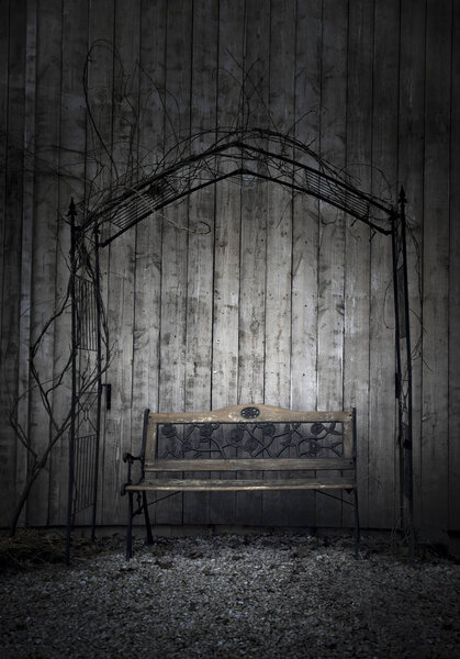 Скамейка в ретро-саду возле деревянного сарая, в холодный день января, под металлической аркой
