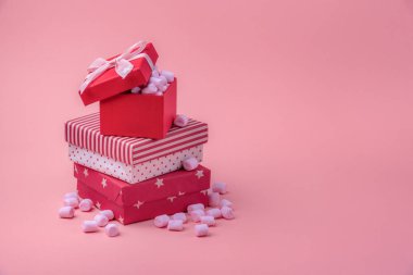 Noel hediye Tema görüntüsüyle tasarımlarında farklı kırmızı, pembe küçük lokum tam bir pembe Kağıt arka plan üzerine sarılmış hediyeler bolca.