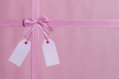 Pembe fiyonk ve şerit ve iki boş etiket Pruvadan asılı olan bir hediye çerçeveye görünümünü yukarıda. Tebrik kartı kavramı.