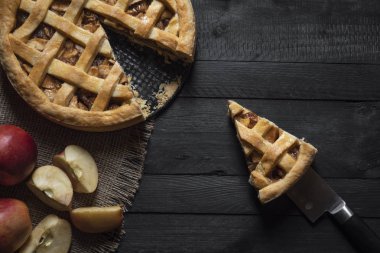 Üstten görünüm bir dilim pasta, bir bıçak, rustik siyah tablo ve tüm pasta ve elma. Ev yapımı geleneksel tatlı. Tatil pasta bağlam.