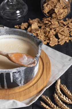 Rustik bir tencerede haşlanmış süt üzerinde kenarları ve buğday hububat ile devrilmiş bir kavanoz üzerine döktüm. Kahvaltı rustik tablo. Sabah rutin.