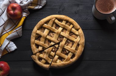 Kırsal mutfak masasının üstünde bir dilim elmalı turta, havlu, elma ve sıcak çikolata. Geleneksel tatlılar. Ev Yapımı Tatlılar.