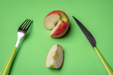Bir kesme dilim, çatal ve bıçak yeşil bir masa üzerine kırmızı elma. Görünümünün üzerinde. Sağlıklı beslenme. Atıştırma zamanı. A vitamini yiyecek. Vegan gıda.