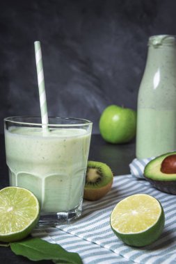 Yeşil smoothie limes, kivi, avokado ve elma, mutfak masasında bir havlu ile çevrili bir cam. Sağlıklı yaşam konsepti. Detoks içecek.