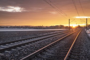 Gün doğumunda Alman kırsalında ve karlı arazilerinde demiryolu rayları var. Kış yolculuğu konsepti. Tren taşıma altyapısı.