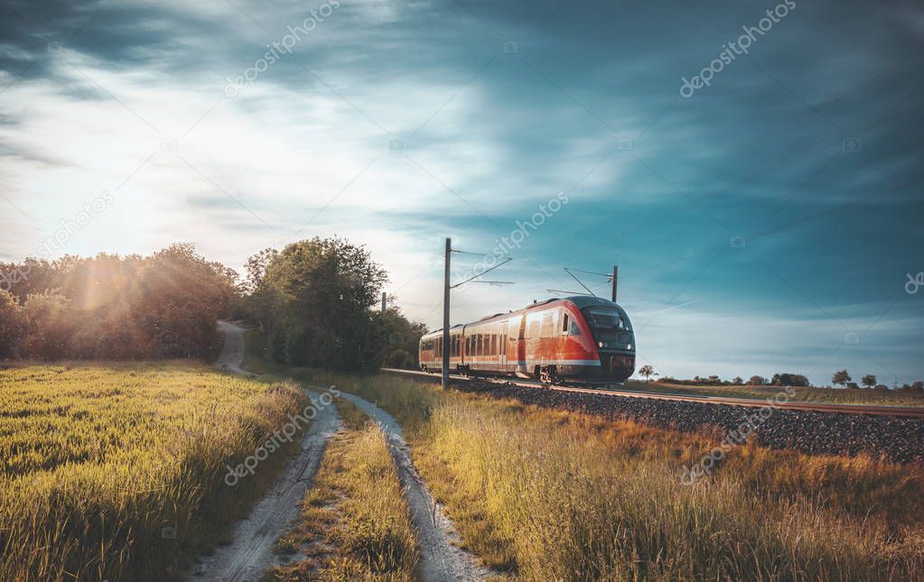 High-speed train moving through nature at sunset