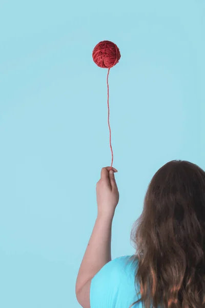 Kvinna som håller flytande röd garn spole som ballong — Stockfoto