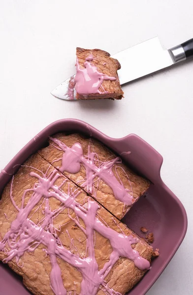 Pink chocolate brownie in a tray on white table