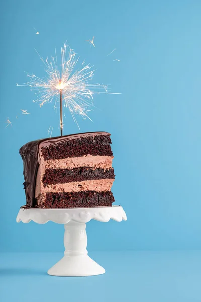 Fetta di torta al cioccolato con sparkler. Torta di compleanno su dorso blu — Foto Stock