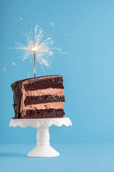 Tranche de gâteau au chocolat avec scintillant. Gâteau d'anniversaire sur fond bleu — Photo