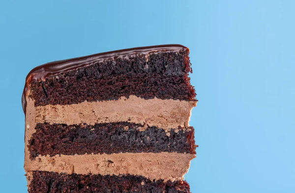Ciocolată felie de tort stratificat. Închidere pe fundal albastru — Fotografie, imagine de stoc