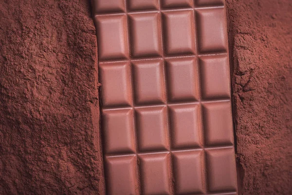 可可粉背景上的牛奶巧克力方块 — 图库照片