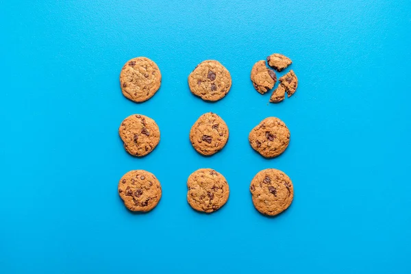 Chocolate chip cookies with brown sugar, symmetrically displayed on blue background. Flat lay with chocolate cookies. Dessert with cocoa and butter.