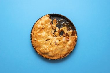 Mavi arka plandaki tepside altın hamurlu Amerikan elmalı turtası. Karamel soslu elmalı tart. Ev yapımı Şükran Günü tatlısı. Sonbahar tatlı yemekleri.