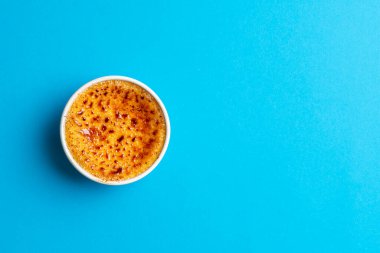 Bekar Ramekins kâsesi. Mavi arka planda creme brulee var. Manzaranın üstünde. Fransız tarifinden sonra nefis ev yapımı tatlı karamelize şekerli krema..