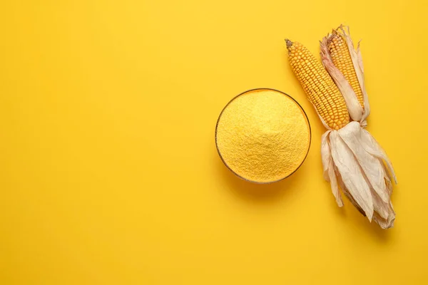 Üzerinde sarı arka planda izole edilmiş bir kase mısır unu olan bir yer. Organik polenta üst görünümü.
