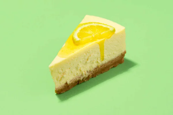 Limon soslu cheesecake dilimi ve yeşil arka planda izole edilmiş limon dilimi. Sarı şuruplu bir dilim peynirli keki yakından çek..