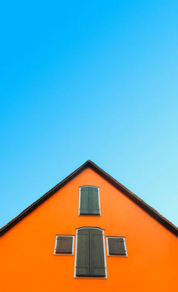 青い空に隔離されたオレンジハウス オレンジの壁と木製のシャッターが付いているドイツの家 屋根のピッチと家のファサードのミニマリストイメージ — ストック写真