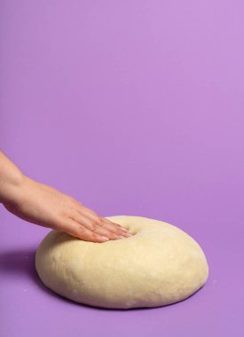 Kadın hamuru test ediyor, pürüzsüz bir mor arka planda izole edilmiş. Ekmek pişirme kavramı. El yapımı mayalanmış hamur. Evde ekmek yapıyorum. Pizza hamuru.