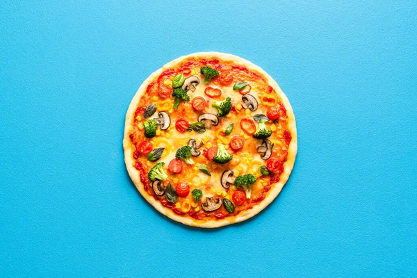 Mavi arka planda izole edilmiş bir pizza primavera 'sı var. Brokoli, şampiyon, domates, mısır ve biberli vejetaryen pizza..