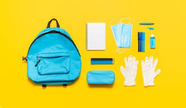 Salgın hastalık konseptiyle okula dönüyorum. Okul malzemeleri, boş bir okul çantası ve koruyucu ekipman maskeler, eldivenler ve dezenfektan. Okulda yeni normal.