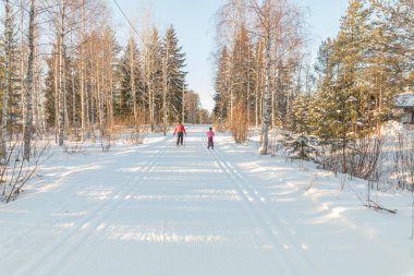 Small child and man in the ski track at winter forest in Finland.