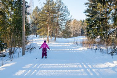 Finlandiya 'da kış ormanlarında kayak pistinde küçük bir çocuk.