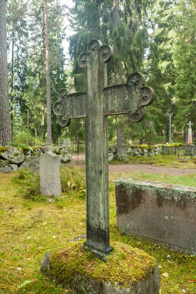 Cross at old semetery in Finland with grave crosses and stones