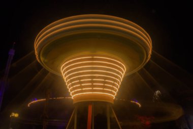 Bir bulanık renkli zinciri atlıkarınca hareket eğlence parkı, gece aydınlatma. Bokeh ve uzun pozlama etkisi