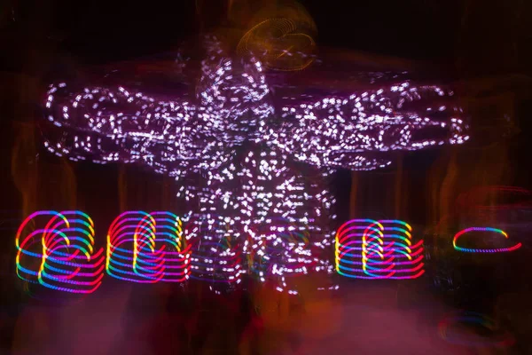 一个模糊的五颜六色的旋转木马在游乐园的运动 夜间照明 Bokeh 和长时间曝光的效果 — 图库照片