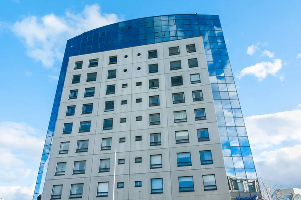 Modern futuristic glass apartment house reflecting the blue sky in windows, Kouvola, Finland.